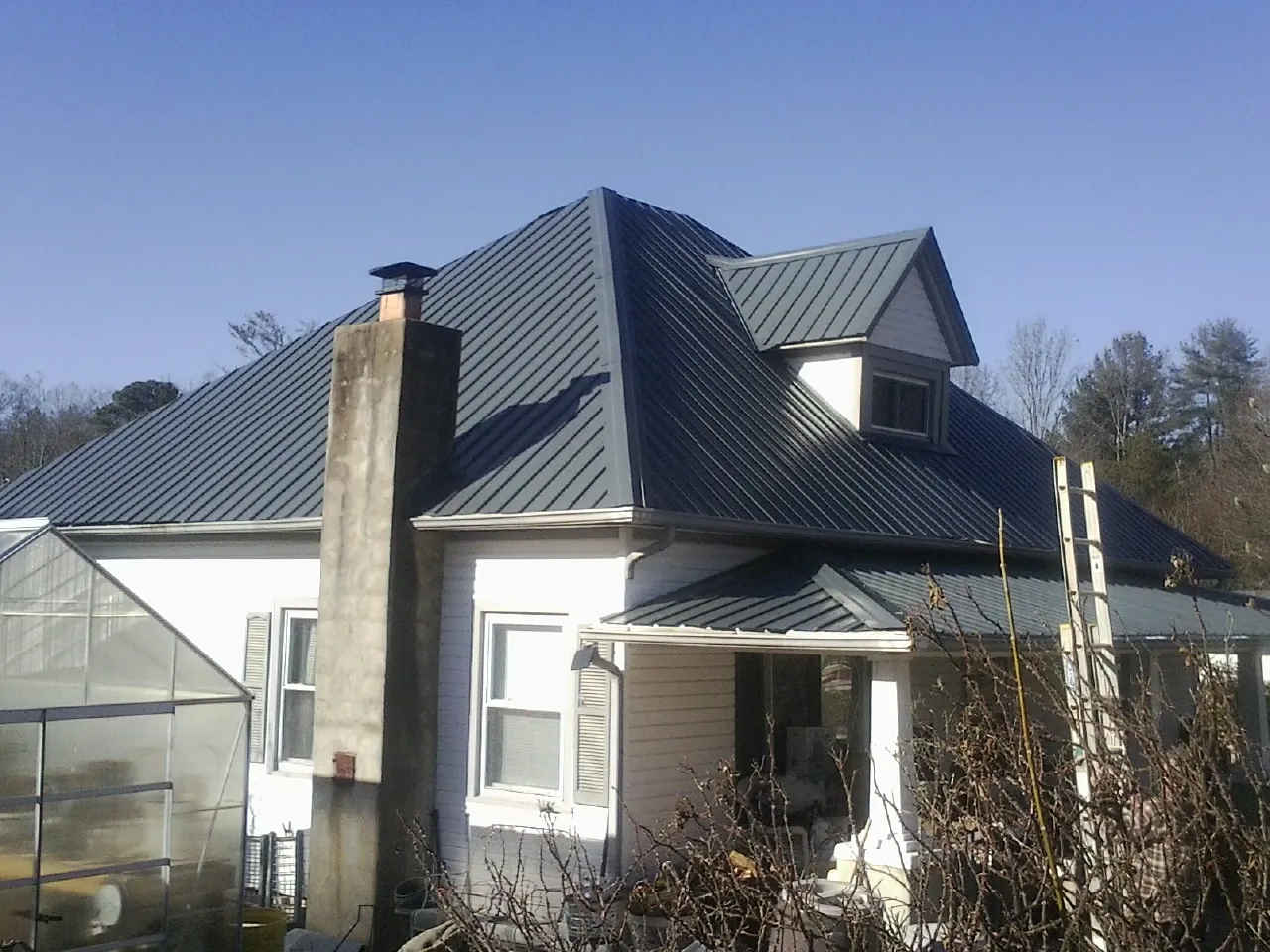 Dark blue standing seam metal roof on a white farmhouse with dormer — Slate & Tile Roof Repair by Roofing Brothers in Metaline Falls