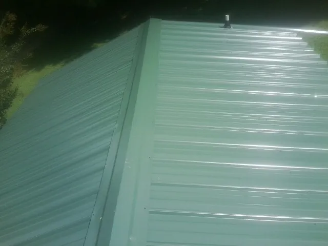 New green metal panels meeting at the ridge of a roof — Flat Roof Repair work by our crew in Metaline Falls