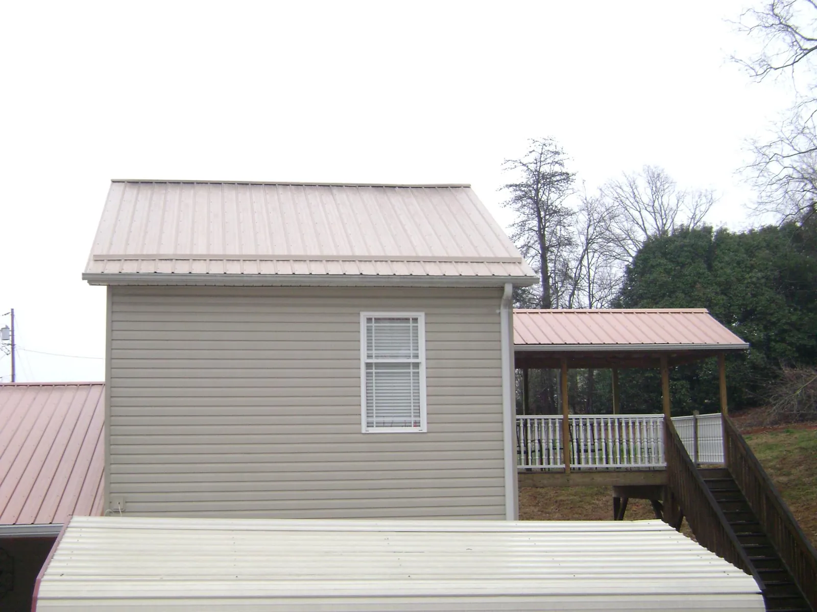 Tan metal roofs on a two story addition and attached porch, from a Roof Replacement job in Metaline Falls