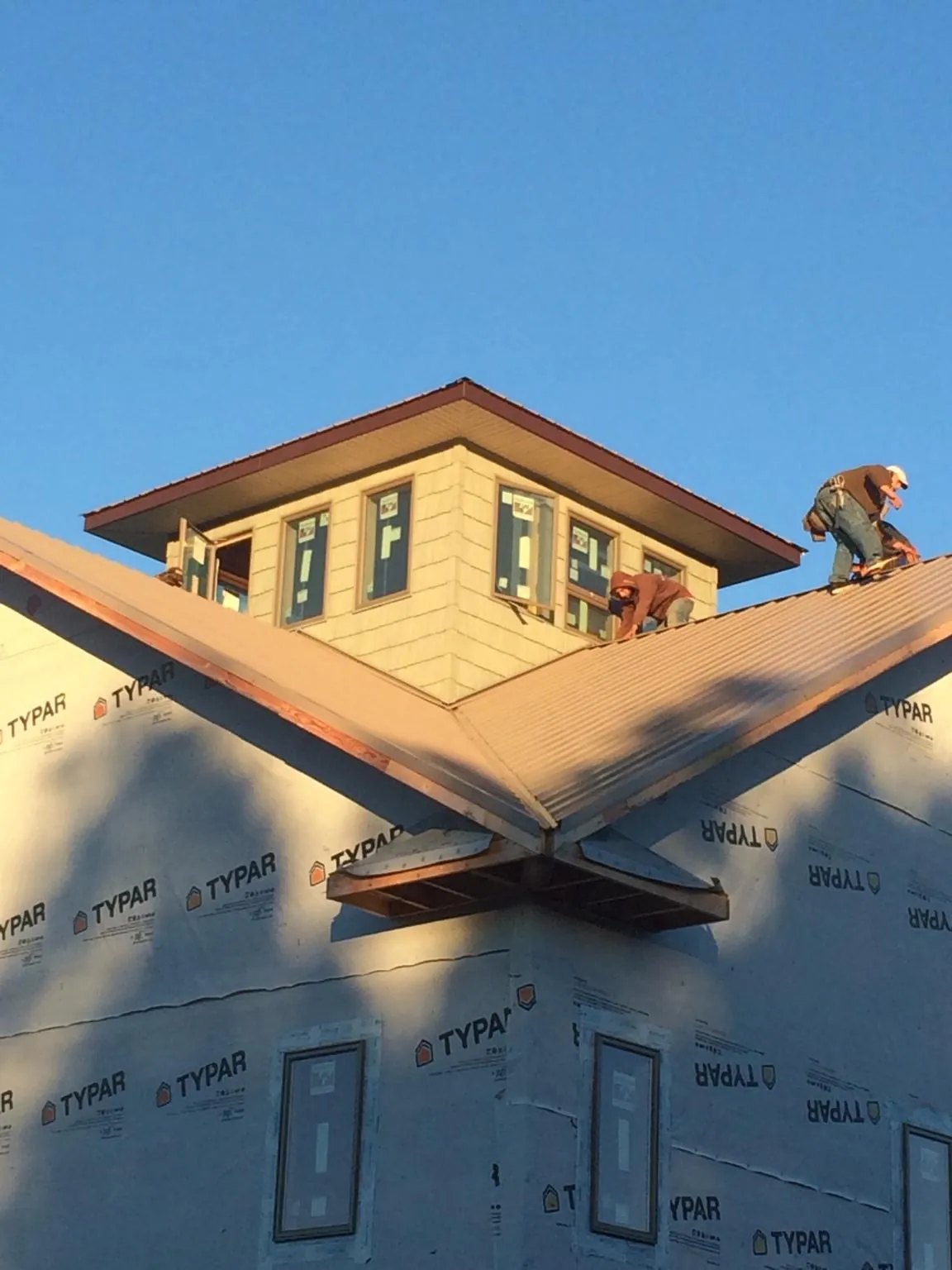Roofers working around a rooftop cupola on a new metal roof at sunset — Roof Waterproofing in Metaline Falls by Roofing Brothers